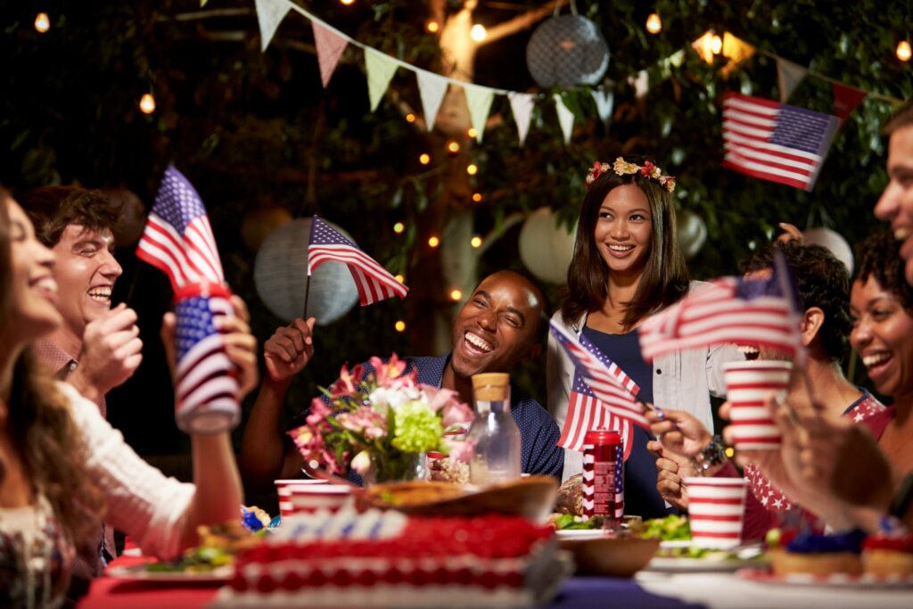 Family, seated around a table, celebrating with US Flags, and gold decorations.